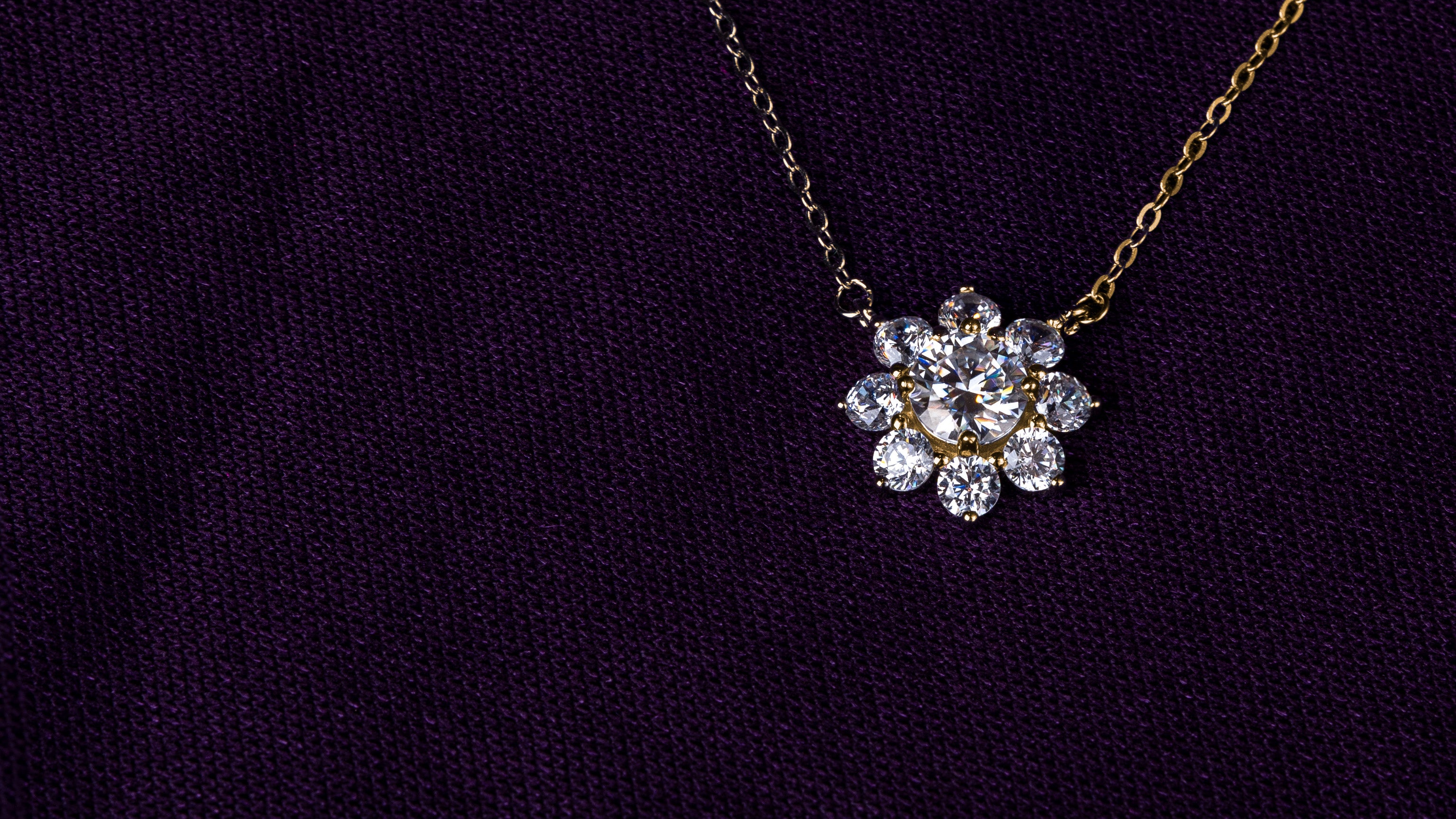Veyelle Neve moissanite snowflake necklace in golden gold on plum velvet backgroundslider_item_w99LJR