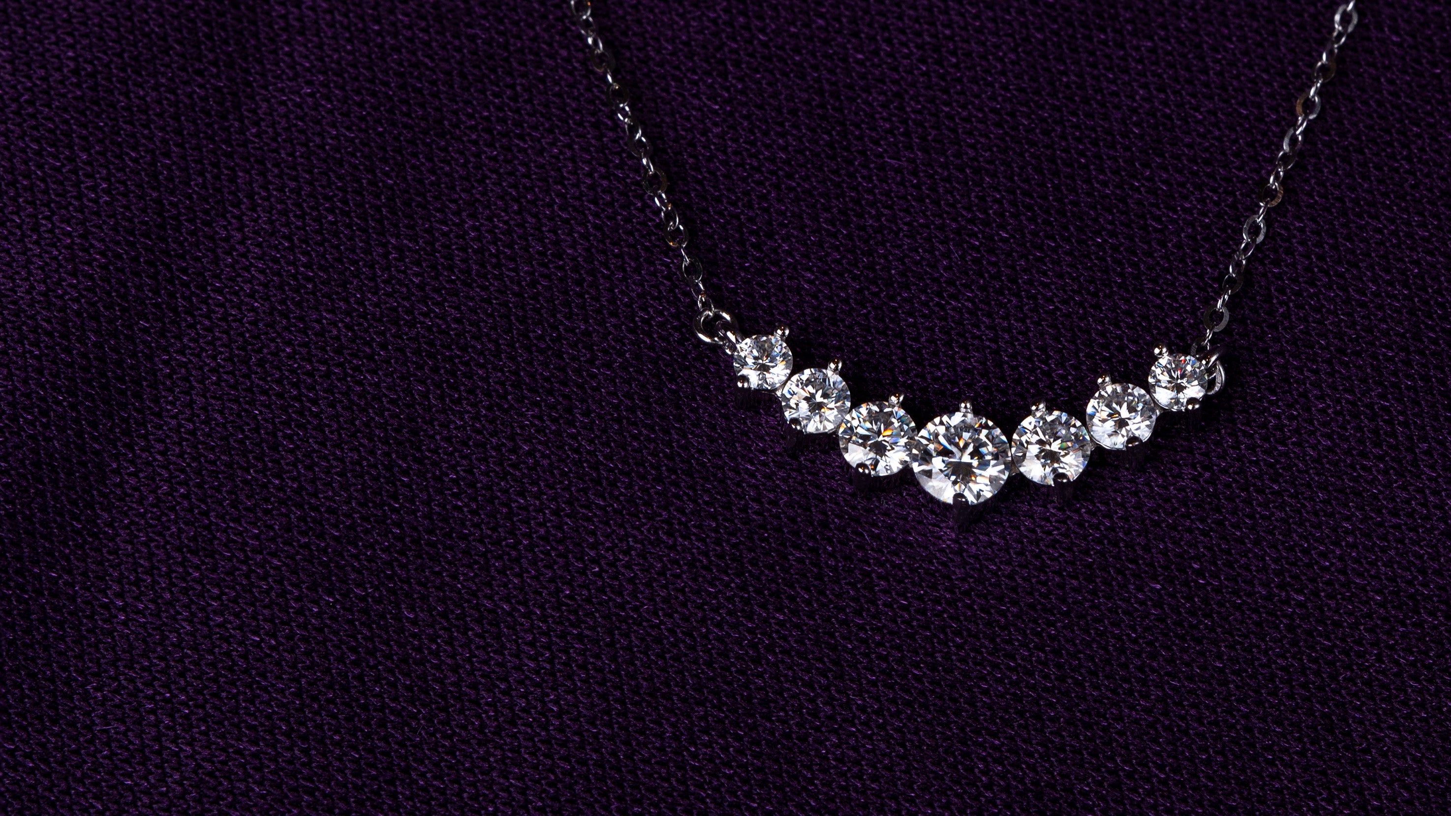 Veyelle Celestine moissanite graduated necklace in white gold on plum velvet backgroundslider_item_jd8fTh