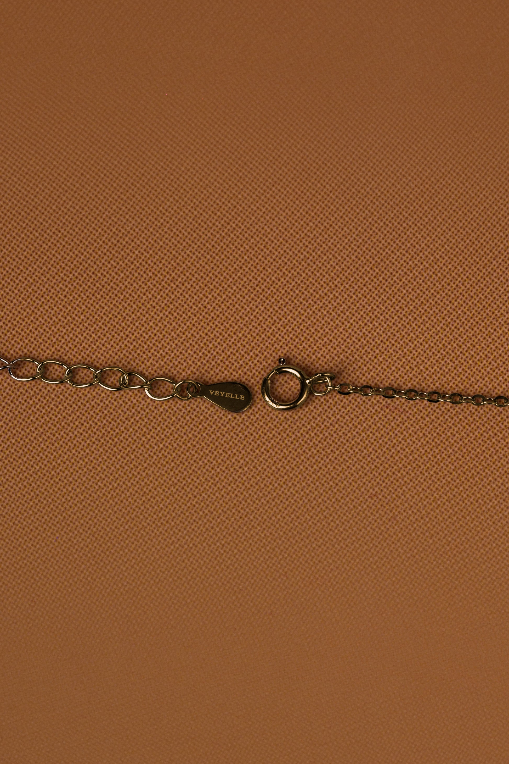 Veyelle necklace clasp detail showing Veyelle logo and lobster clasp in golden gold