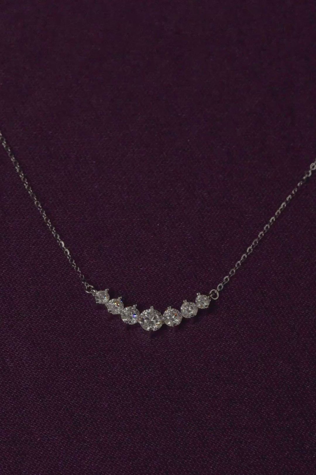 Veyelle Celestine moissanite graduated necklace in white gold on plum velvet background stones firing 